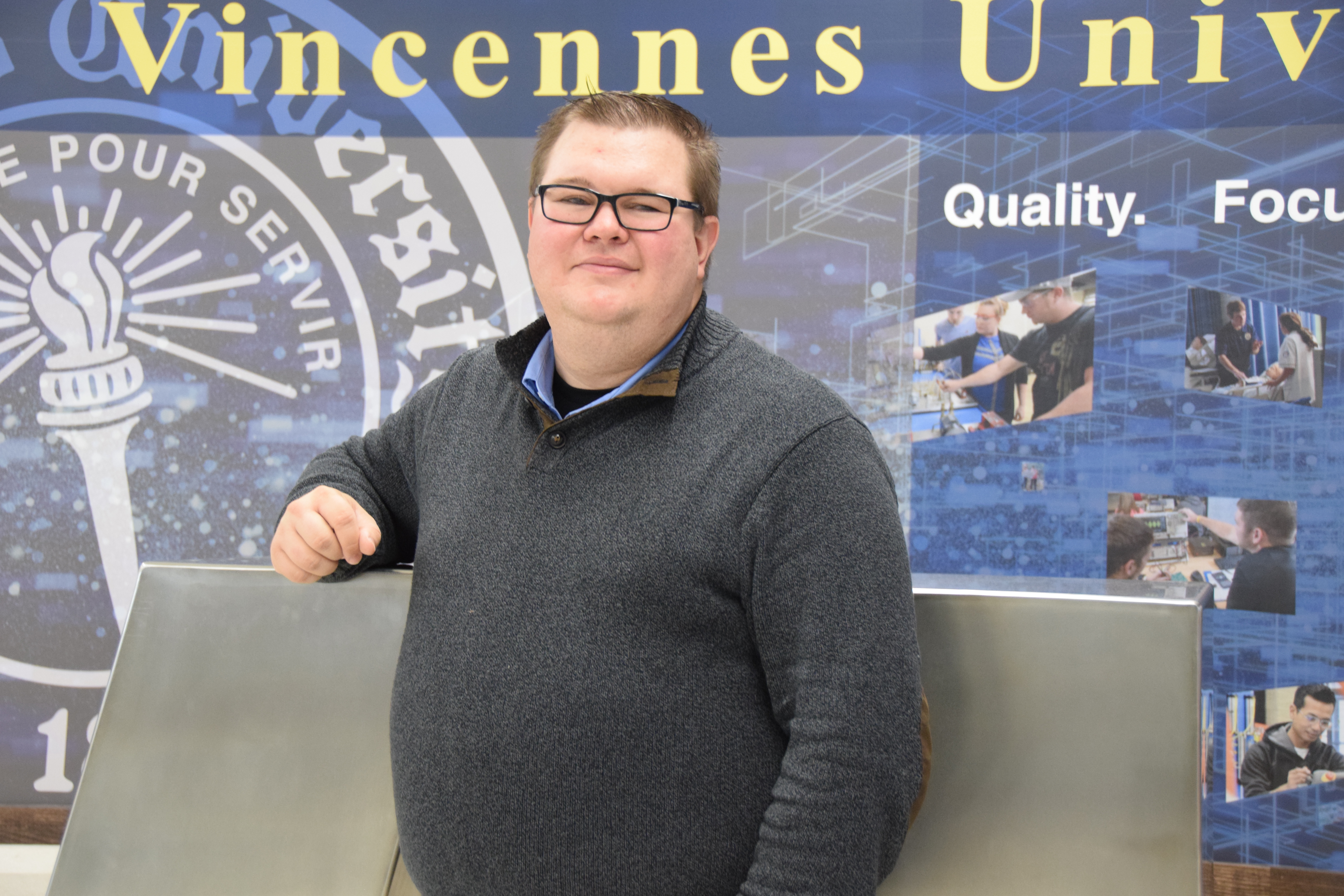 VU alumni Kurt Pangborn standing in front of a VU sculpture in the Shake Learning Resource Center on the Vincennes Campus.